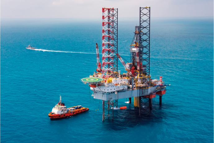Eine Offshore Öl-Plattform, daneben ein Boot im Wasser