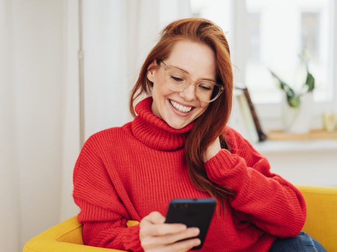 kundenumfrage_-_smiling_girl_looking_at_smartphone__-_c_canva_stockfour.webp